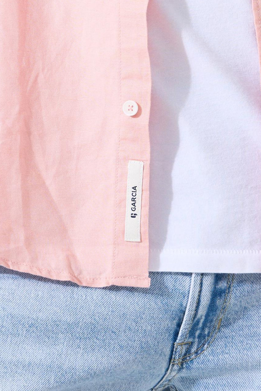 Roze textuurhemd van GARCIA, met knoop en merklabel, gedragen over een wit T-shirt en een spijkerbroek.
