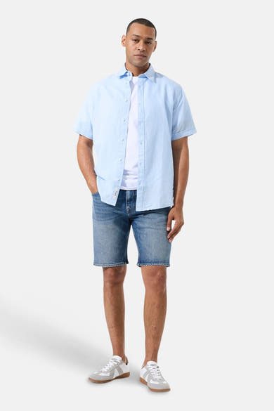 Chemise bleu clair à manches courtes de GARCIA, portée sur un t-shirt blanc et un short en jean.
