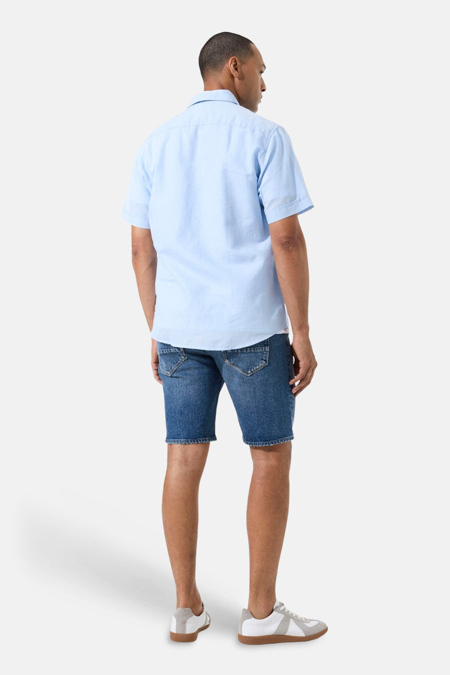 Chemise bleue à manches courtes de GARCIA, vue de dos, portée avec un short en jean et des baskets.