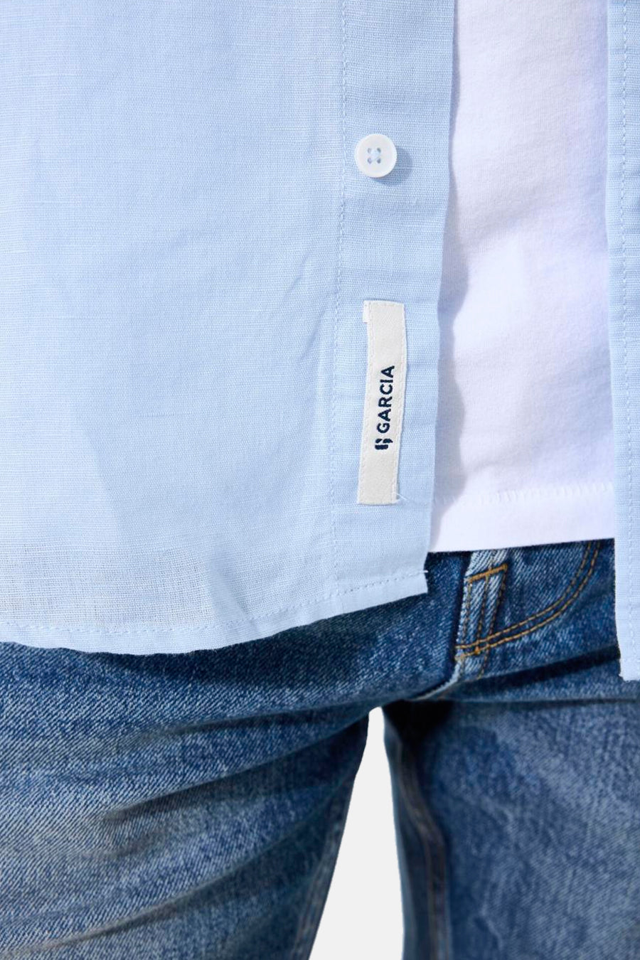 Chemise bleue à manches courtes de GARCIA, avec étiquette de la marque et boutonnage apparent, portée sur un t-shirt blanc et un jean.
