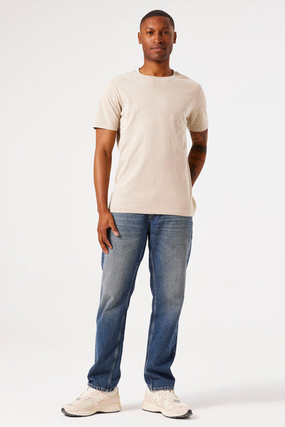Beige T-shirt met korte mouwen van GARCIA, gedragen met een lichtblauwe spijkerbroek en crèmekleurige sneakers.