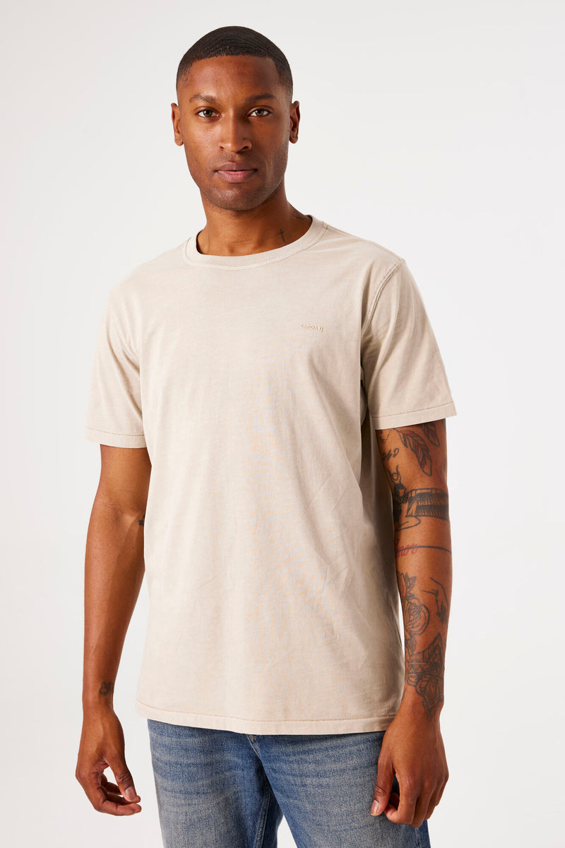 Beige T-shirt met korte mouwen van GARCIA, gedragen met een spijkerbroek, met tatoeages op de arm.