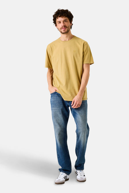 T-shirt à manches courtes jaune de GARCIA, porté avec un jean bleu et des baskets blanches à rayures noires.
