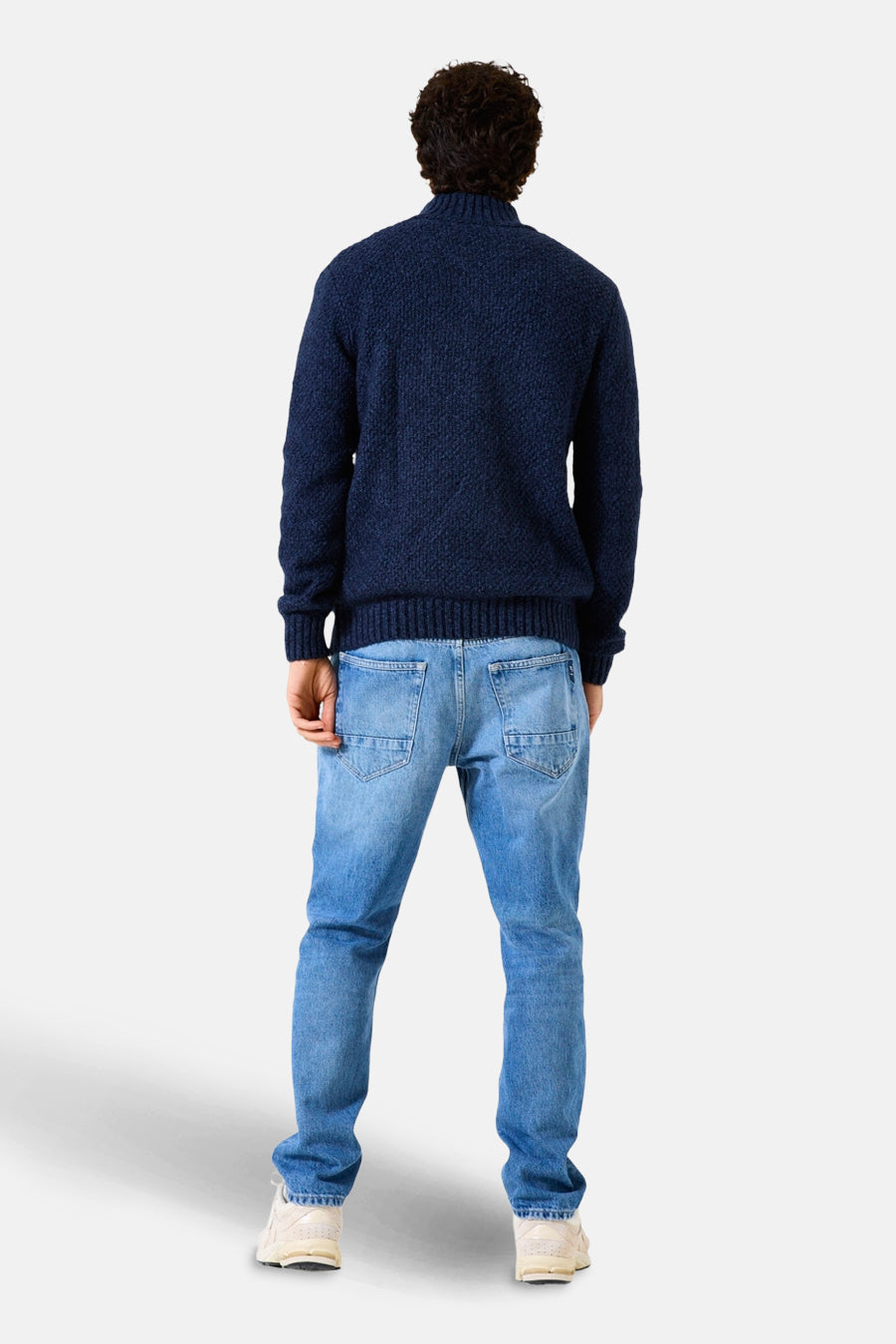Blauwe coltrui van GARCIA, met een kabelpatroon, gedragen met een verbleekte spijkerbroek en sneakers.