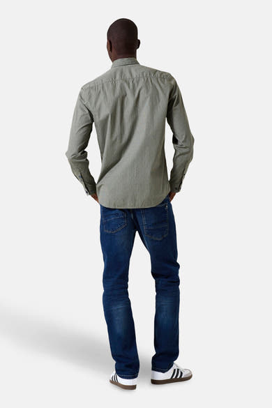 Chemise kaki à manches longues de GARCIA, vue de dos, avec motif discret portée avec un jean bleu et des baskets blanches.