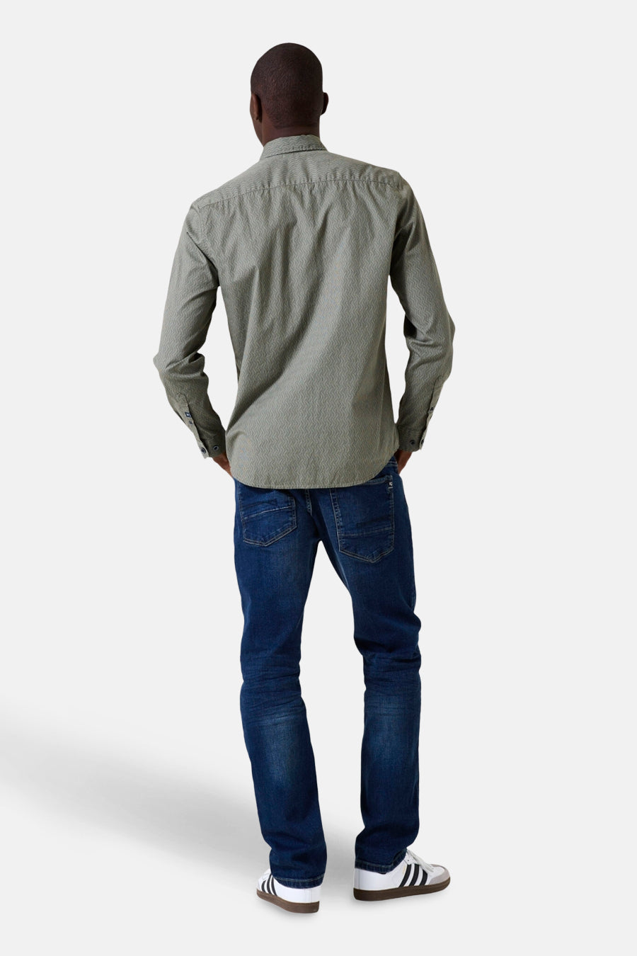 Chemise kaki à manches longues de GARCIA, vue de dos, avec motif discret portée avec un jean bleu et des baskets blanches.