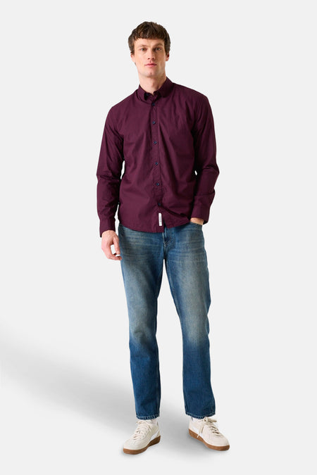 Bordeaux overhemd met lange mouwen van GARCIA, gedragen met een blauwe jeans en crèmekleurige sneakers.