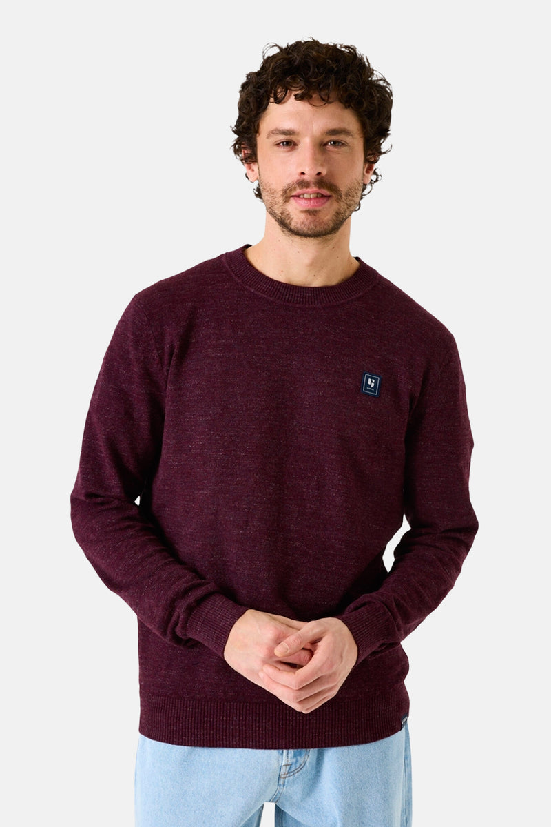 Pull à col rond bordeaux de GARCIA, avec un petit logo sur la poitrine, porté avec un jean clair.
