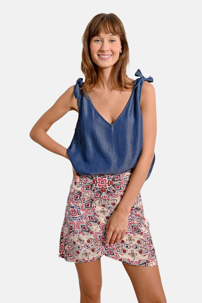 Blauwe spijkerstof tanktop van Molly Bracken met strikbandjes, gedragen met een rok met geometrisch patroon.